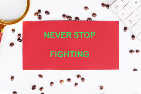 The concept of inspirational and motivational. NEVER STOP FIGHTING written on red paper on a work...