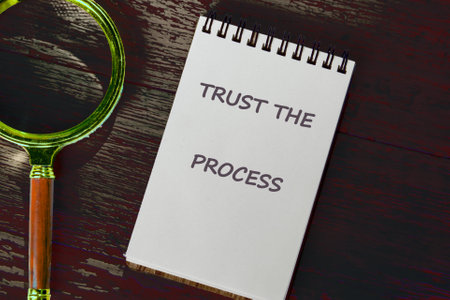 TRUST process, business concept. TRUST THE PROCESS words written on a notebook on a dark background....
