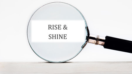 Growth Success Achievement Progress Concept. Words RISE AND SHINE focused through a magnifying...