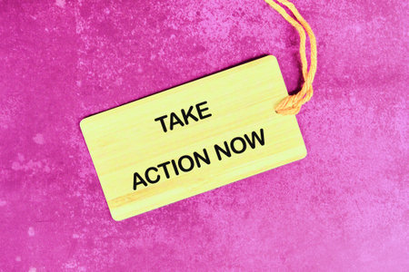 Encouraging motivation, productivity and determination concept. TAKE ACTION NOW written on the tag on a bright abstract background.の写真素材