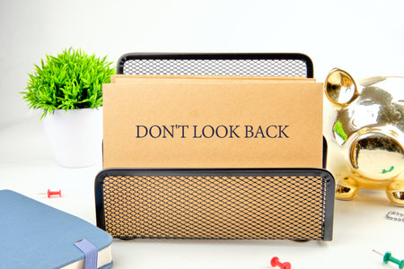 DO NOT LOOK BACK words on paper in a composition with a piggy bank, a notebook and a green plant in...