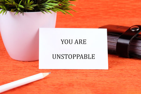 Concept text YOU ARE UNSTOPPABLE written on a card next to a small potted plant and stationery.の写真素材