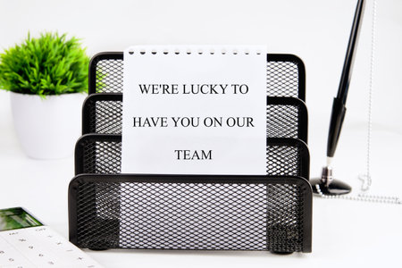 A note expressing gratitude for team members is placed in an organized office space. The setting...