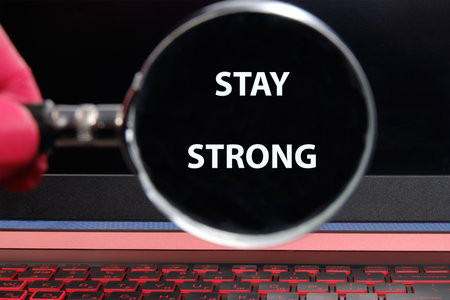 STAY STRONG message through a magnifying glass on a laptop screen in a dimly lit room.の写真素材