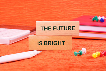 THE FUTURE IS BRIGHT concept words made of wooden blocks on an orange background with stationery...