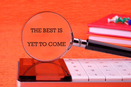 Motivational quotes THE BEST IS YET TO COME focused through a magnifying glass on an orange...