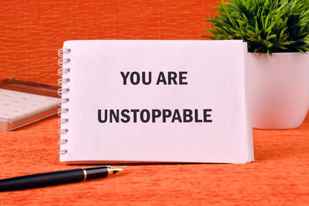 Concept text YOU ARE UNSTOPPABLE on a spiral notebook on an orange background.の写真素材