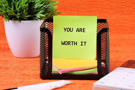 YOU ARE WORTH IT words written on colorful stickers in a black mesh holder.の写真素材