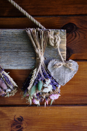 A lovely display of dried flowers tied together with twine, accented by a fabric heart, creates a...