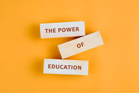 Concept words THE POWER OF EDUCATION assembled from blocks on orange background, top view