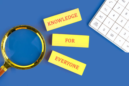 Education Concept text KNOWLEDGE FOR EVERYONE made of wooden blocks on blue background next to...