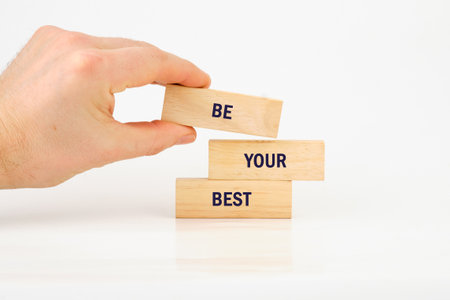 Business motivational concept. Copy space. Words BE YOUR BEST made from blocks with hand on white background.の写真素材