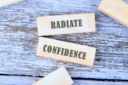 Words RADIATE CONFIDENCE is assembled from blocks on wooden boards, top view.の写真素材