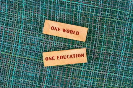 Concept words ONE WORLD ONE EDUCATION made of wooden blocks on fabric background, top view.