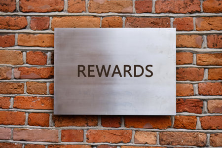 Recognition of successes. Promotion Concept. REWARDS word written on a smooth metal panel is affixed to an old brick wall.の写真素材
