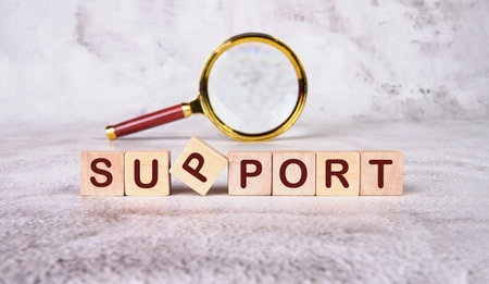 The concept word SUPPORT has been collected of wooden cubes with a magnifying glass in the...