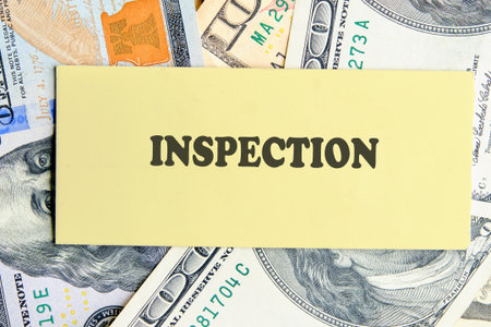 INSPECTION text written on yellow paper on the background of banknotes. Document management concept.