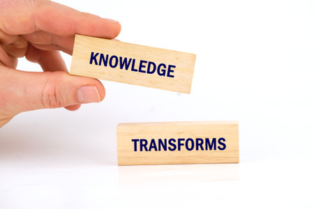 Knowledge learning innovation concept. KNOWLEDGE TRANSFORMS words made from blocks with hand on...