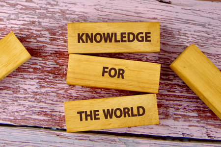 Concepts of business organizations and industries. KNOWLEDGE FOR THE WORLD is assembled from blocks on wooden boards, top view.の写真素材
