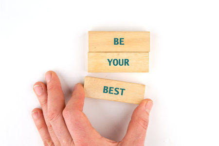 Business motivational concept. Copy space. Words BE YOUR BEST made from blocks by hand on a light...