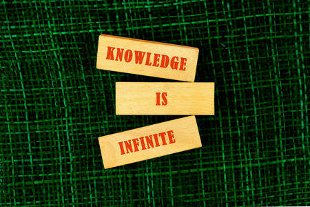knowledge and education concept. KNOWLEDGE IS INFINITE made of wooden blocks on fabric background,...