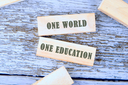 Concept words ONE WORLD ONE EDUCATION is assembled from blocks on wooden boards, top view.