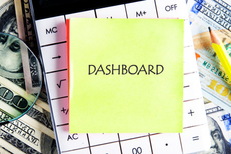 DASHBOARD word written on the sticker on the calculator on the background of banknotes. Data...
