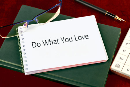 A crisp white notebook rests atop a green journal The phrase Do What You Love is on its page Next to...