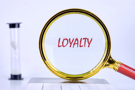 LOYALTY text was revealed through a magnifying glass on a light background that was on the calculator. Customer review satisfaction feedback survey concept.の写真素材