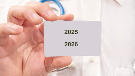 A person wearing a white coat and stethoscope holds a card with the years 2025 and 2026. It suggests...