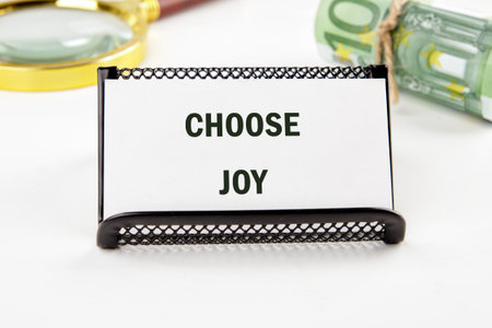 A motivational card reads Choose Joy, with a magnifying glass and Euros nearby. The composition suggests exploring financial freedom with positivity and reflection.の写真素材