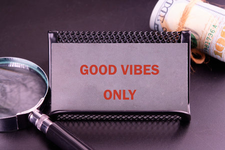 An affirmation card stating GOOD VIBES ONLY is staged with American money and a magnifying glass, invoking themes of positivity, wealth, and scrutiny.の写真素材