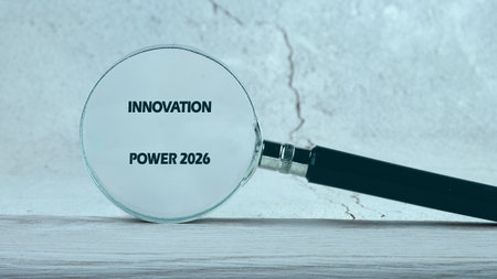 A magnifying glass rests upon a surface of light wood, focused intently on the words INNOVATION POWER 2026 for careful research and analysis.の写真素材