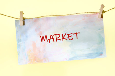 Brightly colored sign hangs on a string, boldly displaying the word Market. This inviting setup creates an atmosphere of excitement and local flavor, attracting people to explore.の写真素材