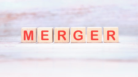 Wooden blocks spell out the word MERGER in bold red letters.の写真素材