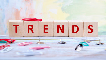 Wooden blocks arranged to spell trends sit prominently on a desk surrounded by colorful paper clips and push pins, creating an inspiring atmosphere for work or study.の写真素材