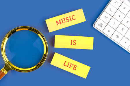Bright yellow cards say music is life alongside a magnifying glass and calculator on a blue background, highlighting musics role in understanding our world and ourselves.の写真素材