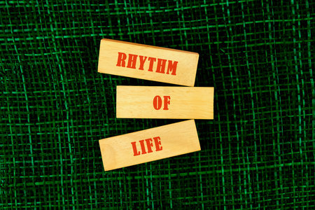 Wooden blocks displaying the words Rhythm of Life rest on a textured green surface. This scene captures a moment of reflection and creativity, inviting thoughts about lifes flow.の写真素材