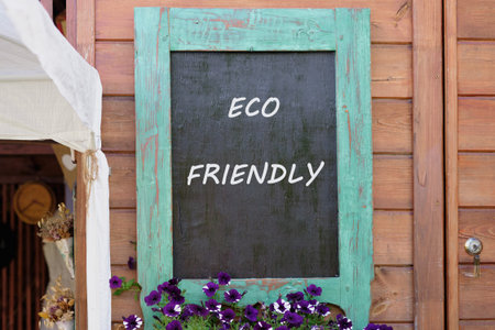 A colorful wooden board highlights the eco friendly message, surrounded by blooming purple flowers.の写真素材
