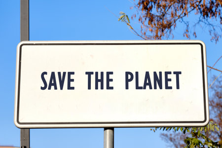 A striking sign stands against a clear blue sky, displaying the powerful words save the planet,...