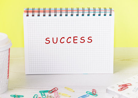A notepad displays the word success in bold letters, surrounded by vibrant paper clips and a coffee cup, creating an uplifting atmosphere perfect for motivation.の写真素材