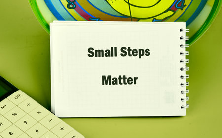 A notepad displaying the phrase Small Steps Matter sits beside a calculator and a colorful clock. This scene represents the importance of gradual progress in achieving goals and success.の写真素材
