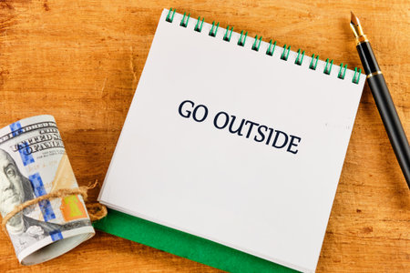 A notebook with a handwritten message invites everyone to go outside and enjoy the beauty of nature. Beside it, a pen suggests spontaneity and adventure.の写真素材