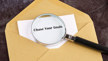 A magnifying glass rests on an envelope, emphasizing a note declaring the need to chase your goals....