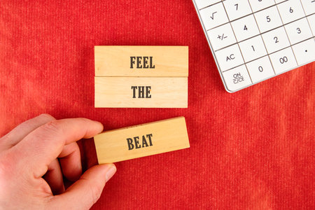 Hand holding wooden blocks with words that inspire creativity on a bright red table. Nearby, a calculator hints at an artistic atmosphere where numbers meet expression.の写真素材