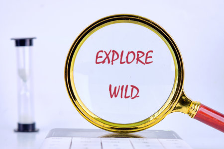 A magnifying glass focuses on the words explore wild, symbolizing the spirit of adventure and curiosity about the natural world and its untamed beauty.の写真素材