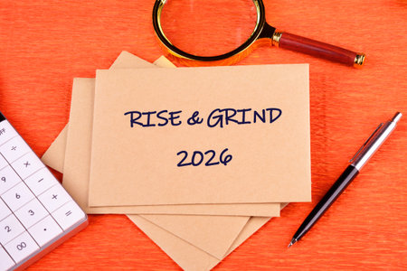 A workspace showcases brown notes with the words RISE GRIND on a vibrant orange background....