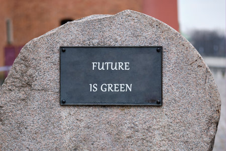A large stone features the powerful words Future is green, nestled in a calm park. This message encourages eco-friendly choices amidst nature, inspiring visitors to reflect.の写真素材
