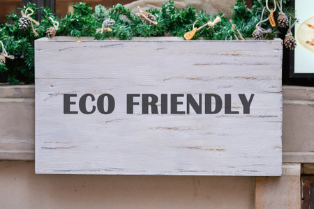 A sign reading eco friendly hangs above a festive display, surrounded by green foliage and rustic decor, showing a commitment to sustainability in a lively urban area.の写真素材