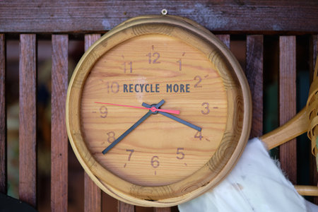 A charming wooden clock adorns a rustic wall, featuring the inspiring message to recycle more. Its...